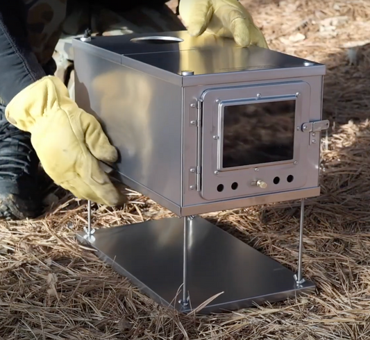 Wstove Titanium Tent Wood Stove with Front Window and official Wild Wild West logo, and user wearing gloves