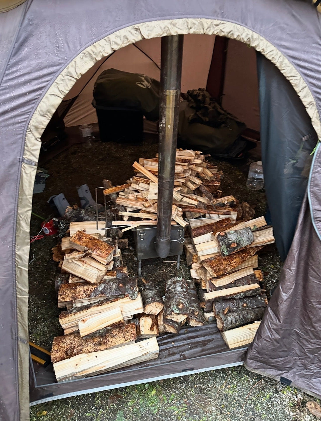 Firewood pile around a hot tent wood stove while camping outdoors