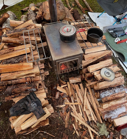 Firewood stack around a tent wood stove in campsite