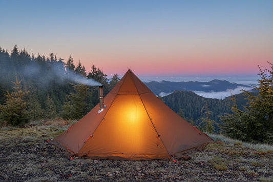 Hot tent with wood stove inside in mountain campsite