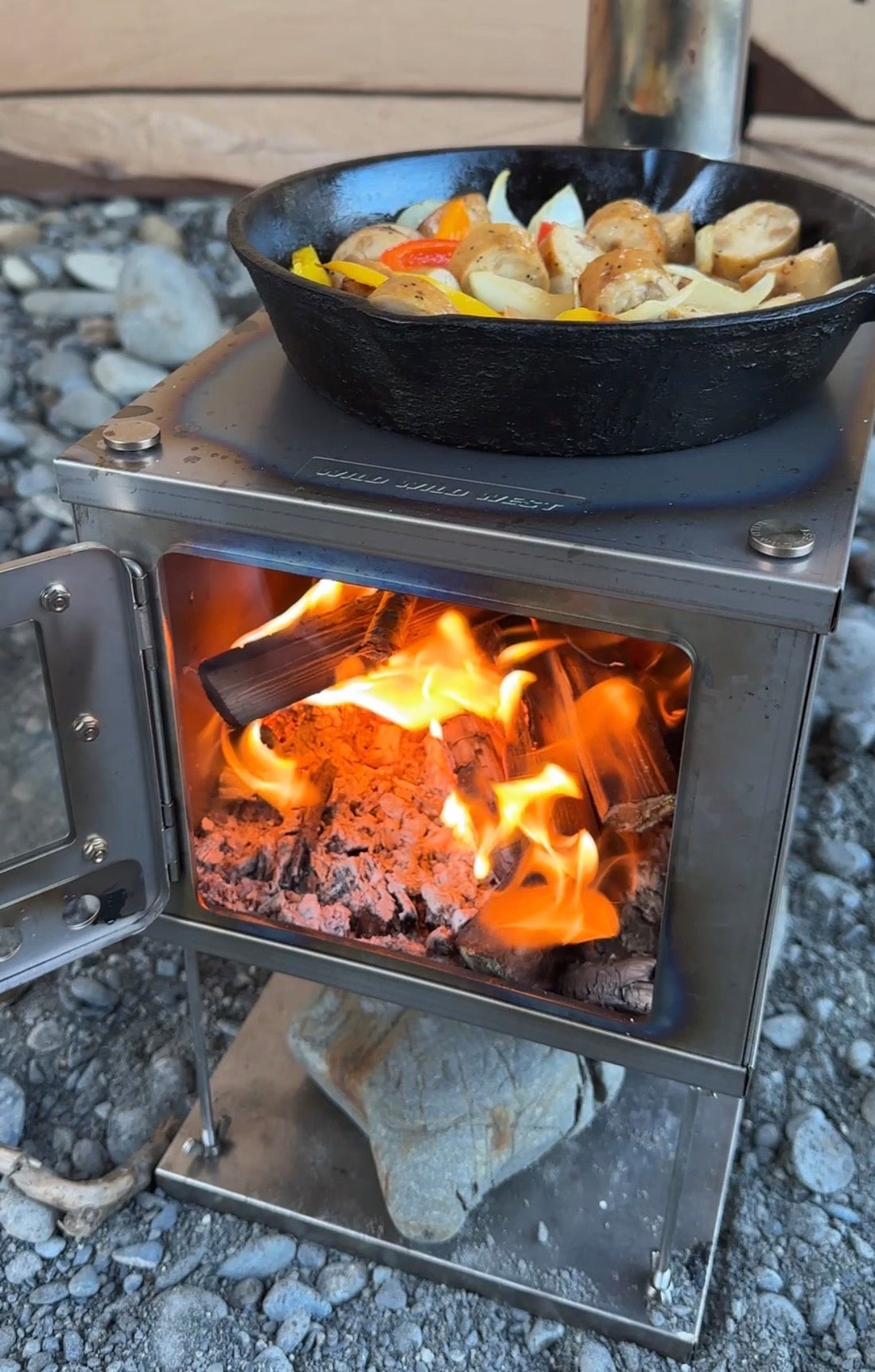 Hot coals in tent wood stove while food is cooking on the stovetop