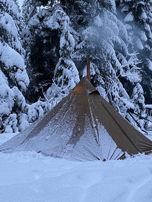 Hot tent with wood stove in the forest camping in wet snow