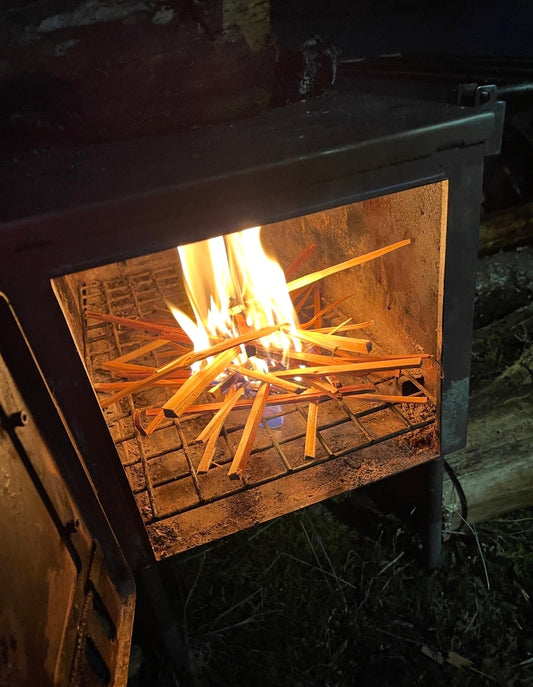 Starting a tent wood stove with dry cedar kindling 