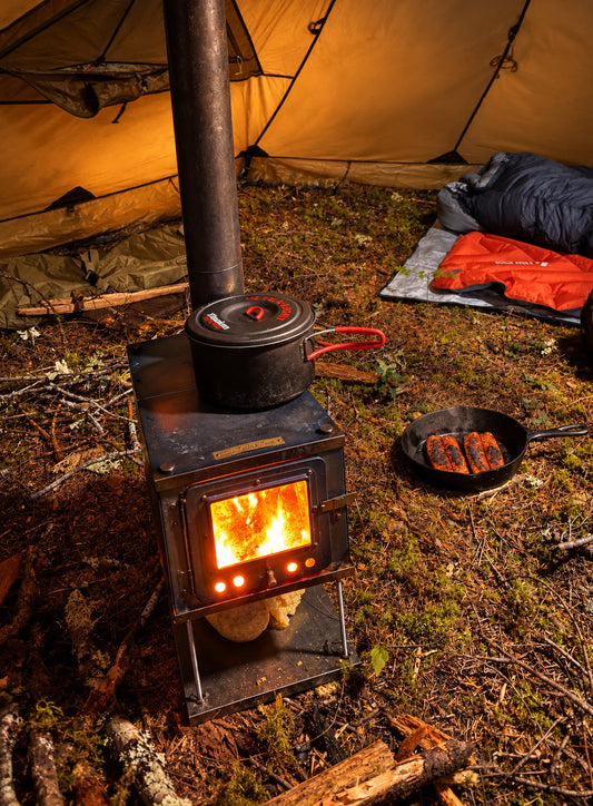 Tent wood stove inside shelter burning firewood