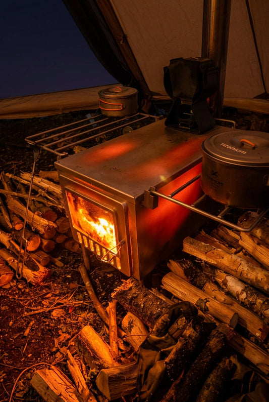 Tent wood stove glowing red while hot tent camping with firewood from the forest inside