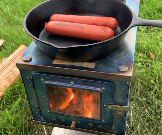 Titanium tent wood stove cooking food in cast iron pan