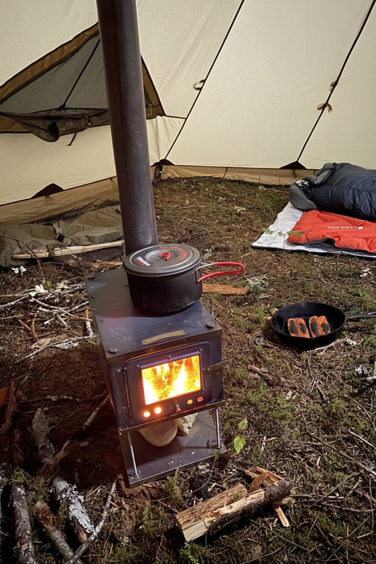 Wood stove inside tent cooking food in campsite